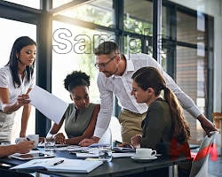 Four colleagues collaborating around a conference table in a modern office setting.